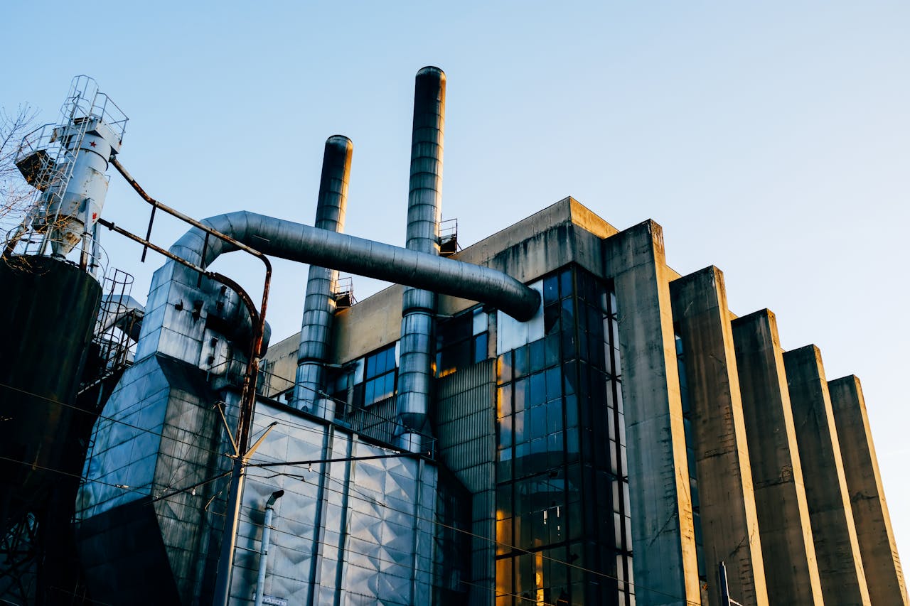 services-02 A contemporary industrial factory structure with smokestacks at sunset, showcasing modern architecture.